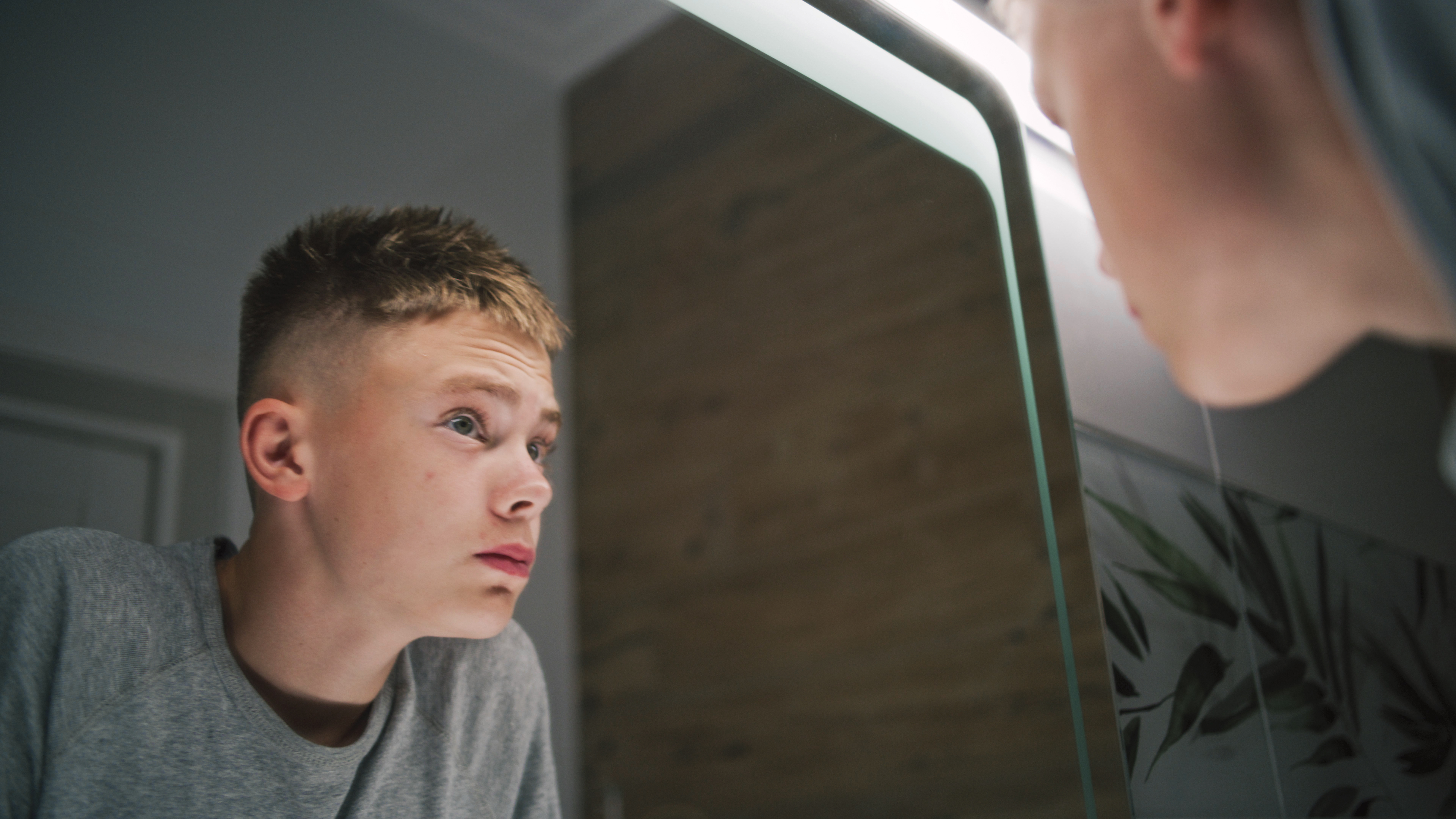 Adolescent boy looking in a mirror