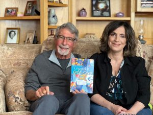 Gerald Corey and Michelle Muratori sit together holding a copy of Counselor Self-Care, second edition