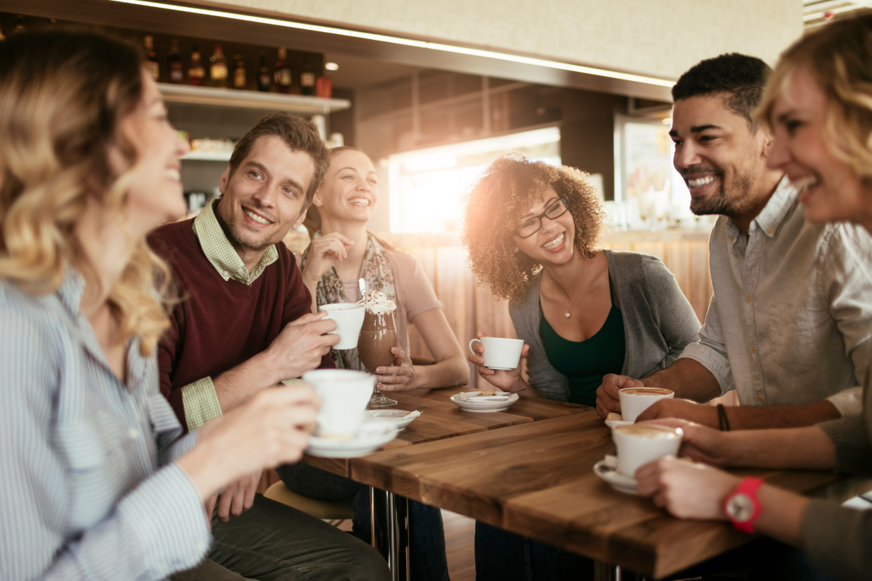 A group of adults sitting around a table drinking coffee and smiling