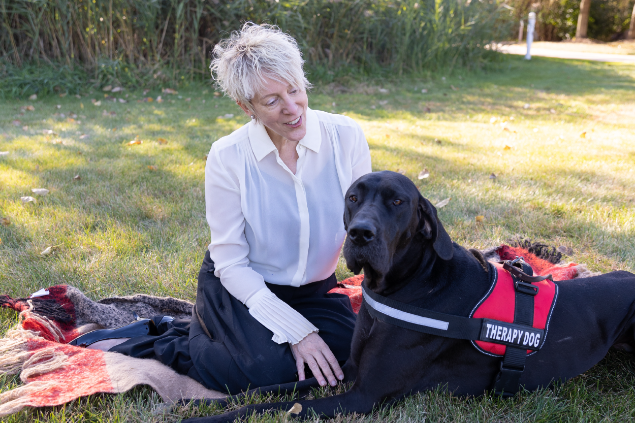 Licensed professional counselor Donna Gluck sitting on a blanket with her therapy dog, Talia 