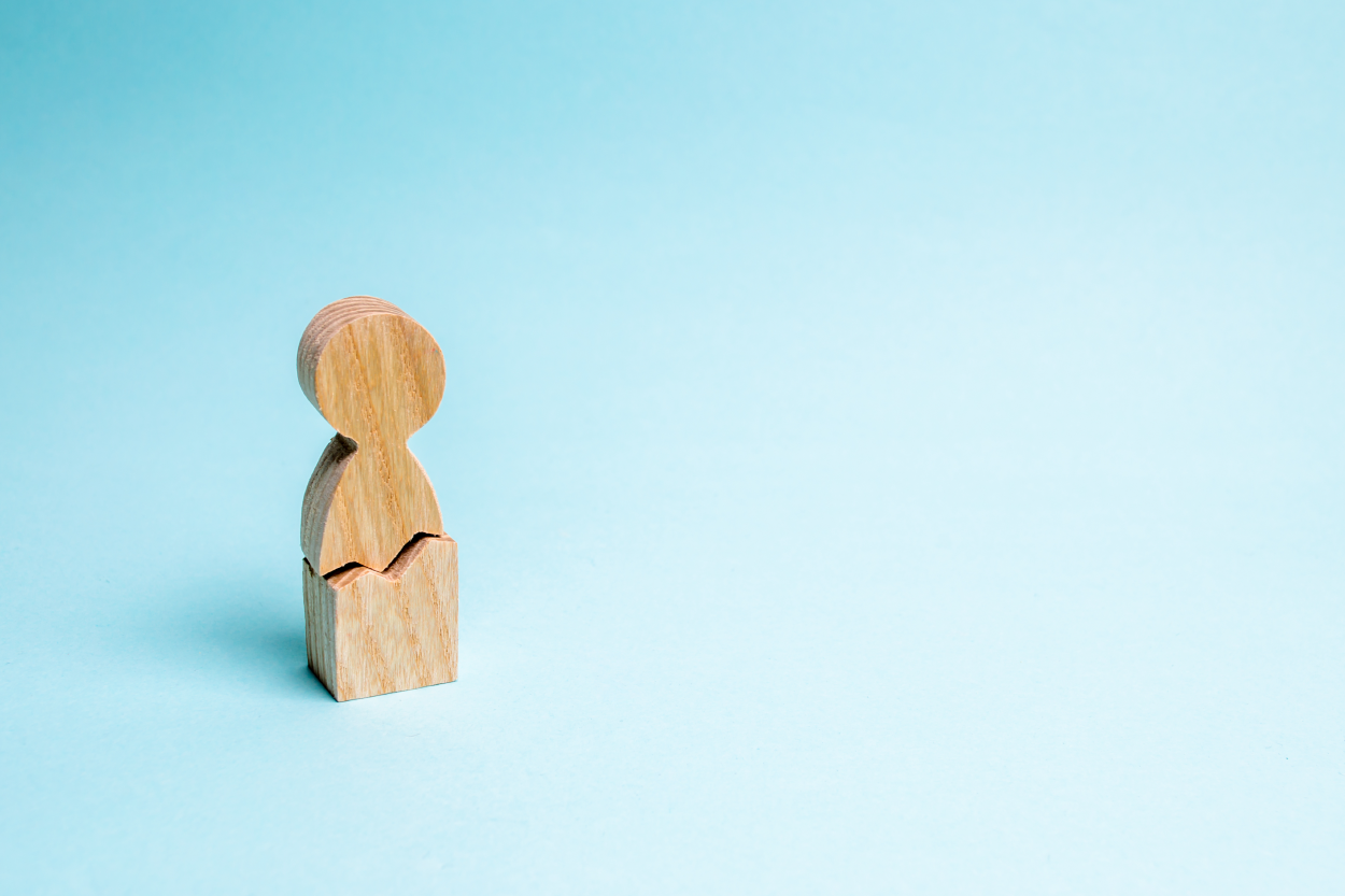 wooden block figure that is broken in the middle; standing against a blue background