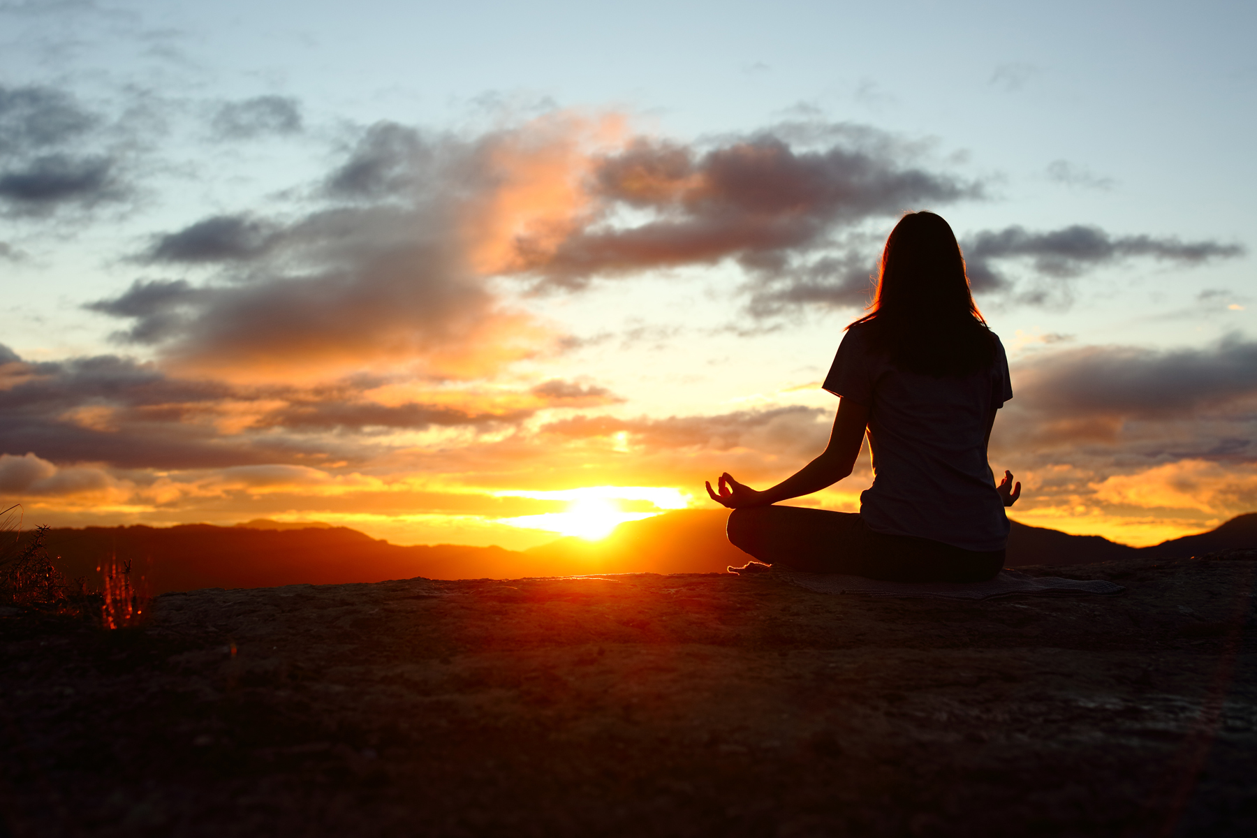 wellness - woman meditating at the sunrise